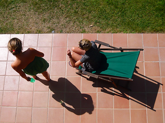 long shadows of sunbathersand a deck chair on a tiled patio