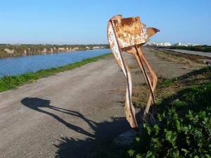 rusty sculpture of a flamingo on a canal side