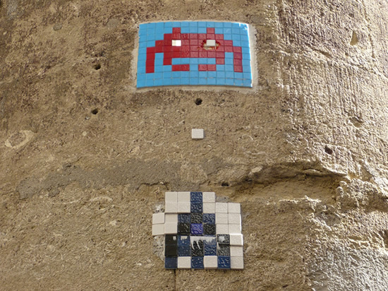 tiled mosaic of space invaders on a stone wall