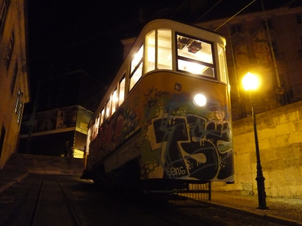 tram on a steep hill at night illuminated by steet lamp and light from windows